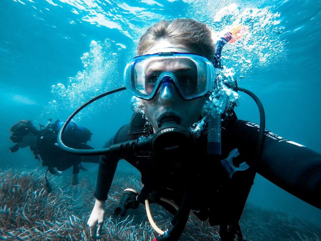 diving instructor teaches students to scuba dive in swimming pool. couple getting first experience with scuba diving under the guidance of experienced recreational diving instructor on vacation.